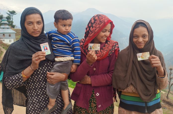 Three mute sisters displaying their voter identity card.