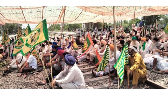 Farmers sit on railway tracks during a protest at the Shambhu border, in Patiala district, on Saturday.