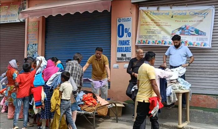 Members of NSG Trust distributing clothes during a camp in Jammu on Friday.