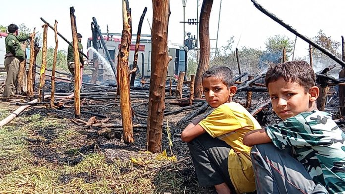 Two nomadic children sit by the side of their hutment that got completely damaged in a devastating fire in Arnia on Wednesday.