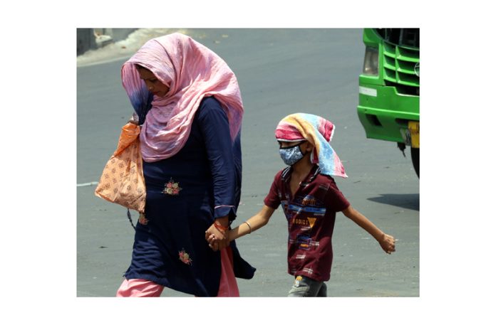 A woman with her child walk on a Jammu city road with their heads covered in scorching heat. -Excelsior/Rakesh