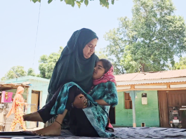 A mother carries her child, suffering from a mysterious disease, in her lap in Panassa village of Reasi district.