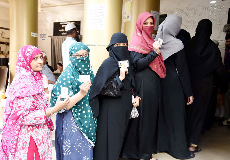 Voters displaying identity cards while standing in the queues to cast their votes at a polling booth during the 3rd Phase of election at Lokhandwala General Hospital in Ahmedabad on Tuesday. (UNI)