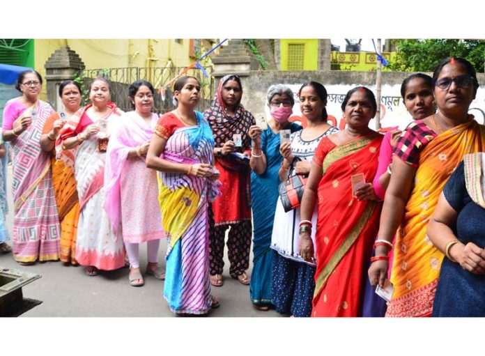 Women voters displaying identity cards while standing in the queue to cast their votes at Jagaddal in North 24 Parganas district of West Bengal on Monday. (UNI)
