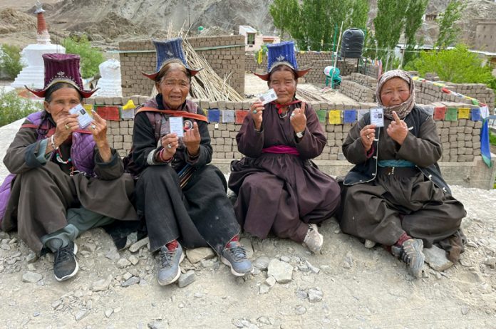 People displaying voter cards and ink marks after casting votes in Leh on Monday.