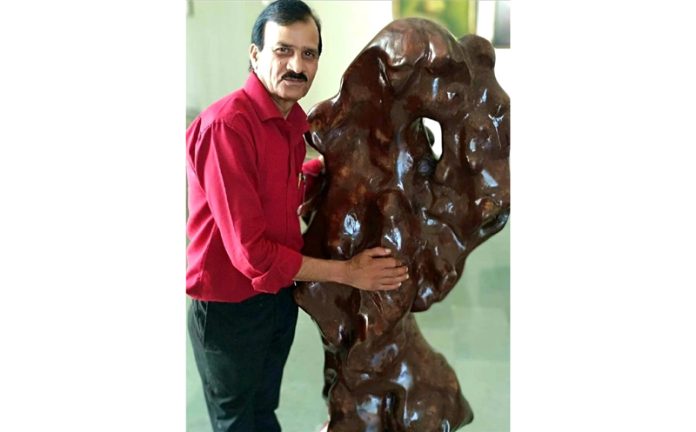 Sculptor Ganesh Kumar Sharma posing with one of his art work.