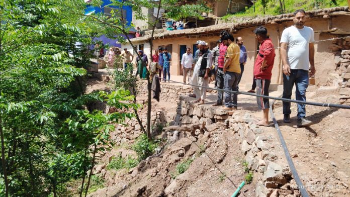 People stand near houses which developed cracks in Dalwass area of Ramban on Thursday.