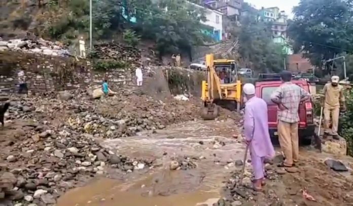 A JCB clearing debris from the road after flash floods wreaked havoc in Thathri town on Friday. —Excelsior /Tilak Raj