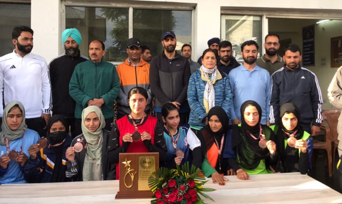 University of Kashmir players displaying trophy and medals while posing with dignitaries.