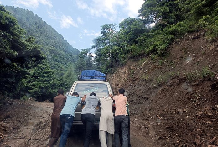 Passengers pusing a vehicle on slippery Thannamandi - DKG Road in Rajouri. -Excelsior/Imran