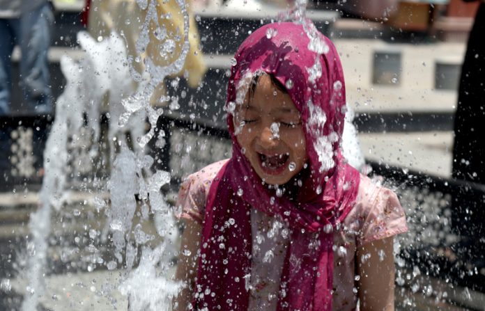 Amidst sweltering heat in the Valley, a girl finds relief at a fountain near Srinagar’s iconic clock tower. Excelsior/Shakeel
