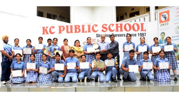 Students and management of KCPS posing along with trophy and certificates. 