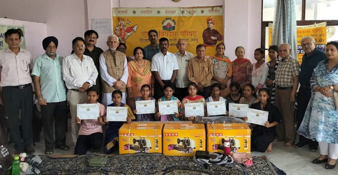 Students of tailoring course posing with BVP office bearers while displaying their certificates.