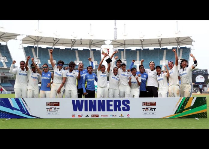 Indian women team posing for group photograph while holding trophy after winning test match against South Africa.