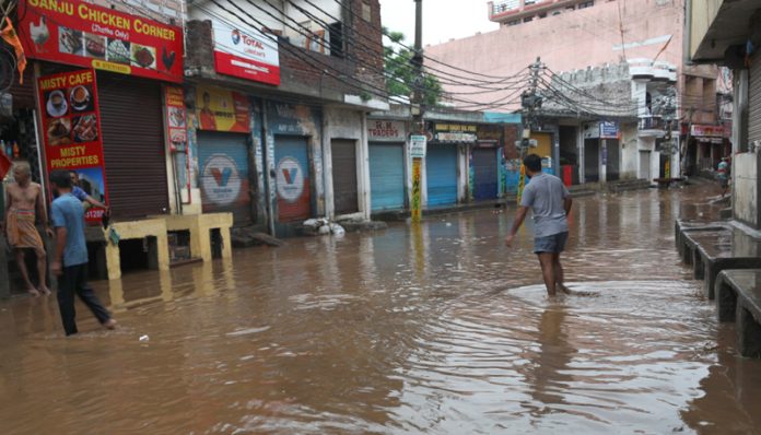 A man walking through flooded lane at Sanjay Nagar in Jammu on Thursday morning. -Excelsior/Rakesh