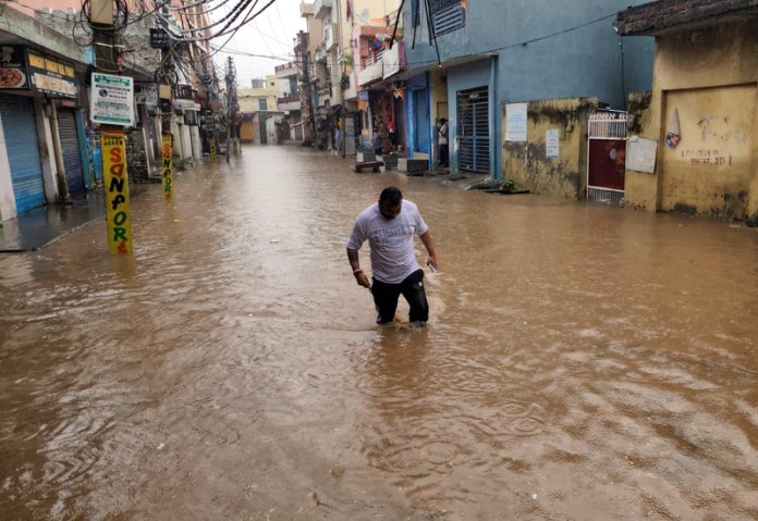 A man moving through knee-deep water in a lane at Nanak Nagar after heavy rain in Jammu on Wednesday. -Excelsior/Rakesh