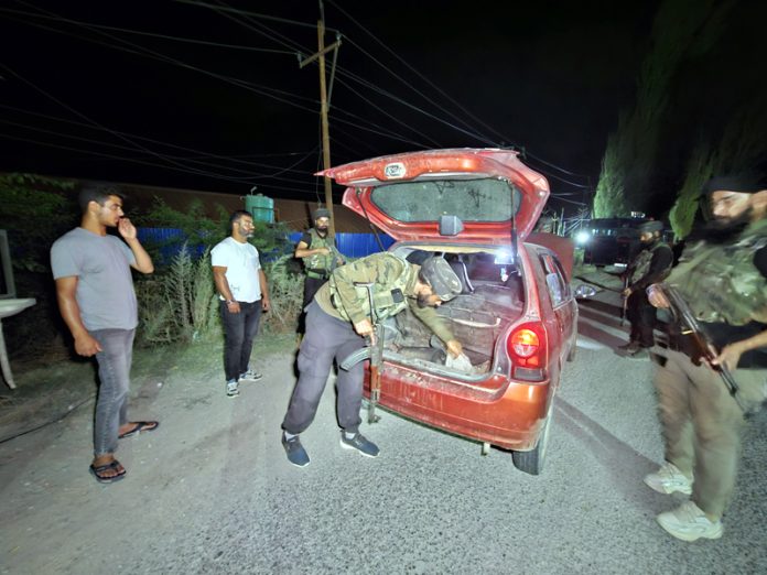 Security personnel checking a vehicle in Baramulla on Tuesday. -Excelsior/Aabid Nabi