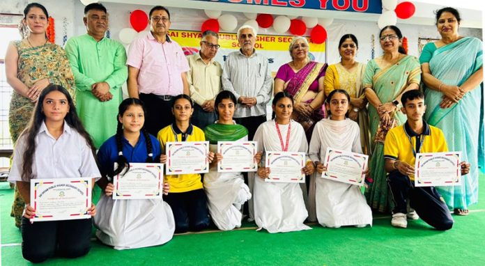 Students posing with certificates and dignitaries during a debate competition.