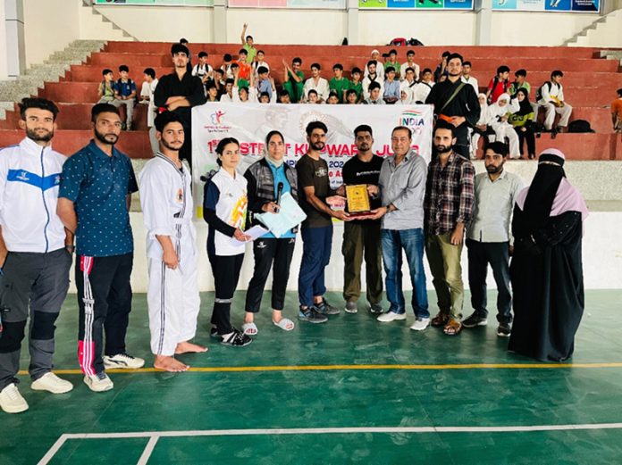 Judo players posing with memento and dignitaries.