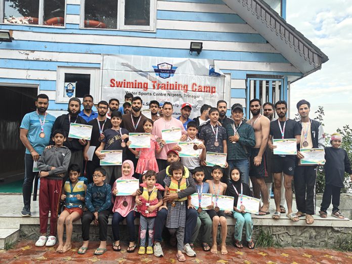 Young swimmers posing along with certificates and dignitaries.