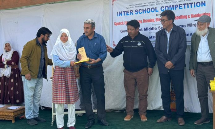 A student receiving memento from dignitaries during inter-school competition.