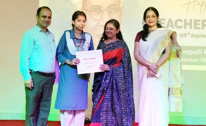 APS Akhnoor student receiving certificate from dignitaries during event.