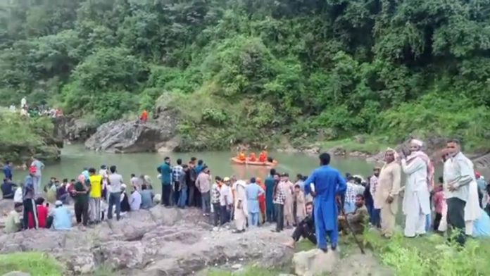 People, police and SDRF men involved in search of dead body of drowned youth in Manjakote river. -Excelsior/Imran