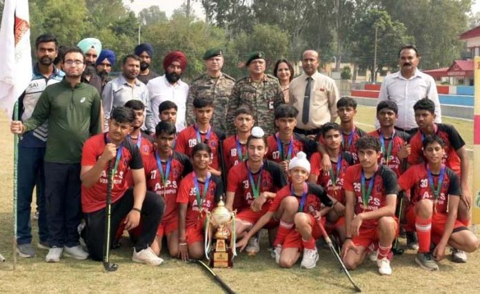 APS Udhampur Hockey team posing along with a trophy and dignitaries.