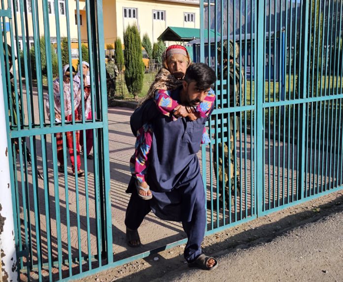 Man carries elderly mother to cast her vote in Uri area of Baramulla district. -Excelsior/Aabid Nabi