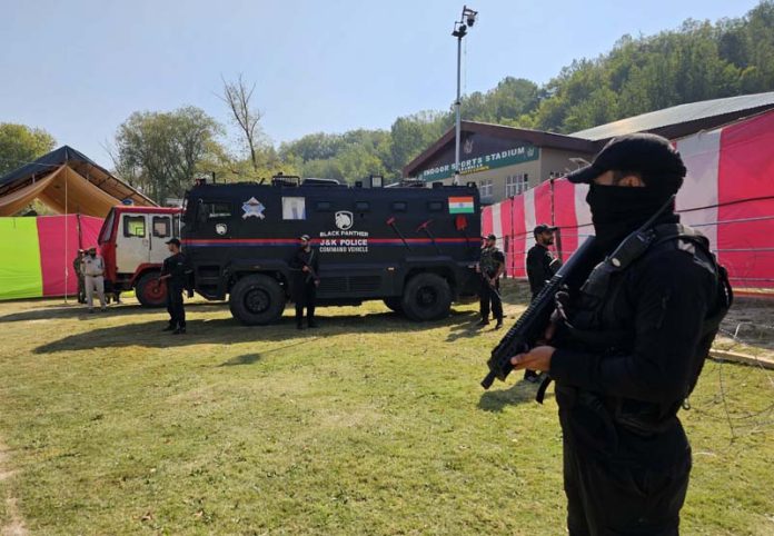 Security men stand guard outside a Polling Station in Baramulla on Monday. -Excelsior/Aabid Nabi