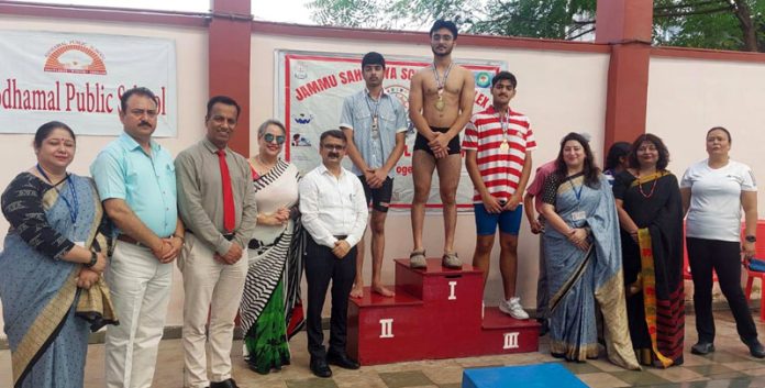 Swimmers posing on podium during competition.