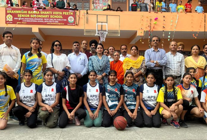 Girl players along with others pose for a photograph at the start of UT Level Inter-District Basketball Tournament for all age group girls in Udhampur.