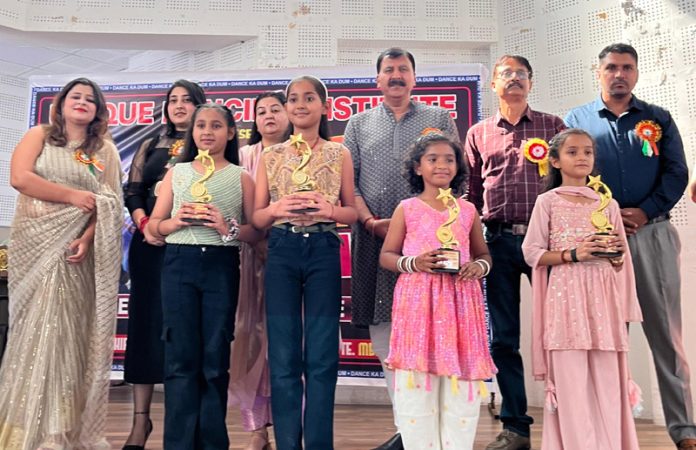 Students displaying trophies while posing with dignitaries during an event.