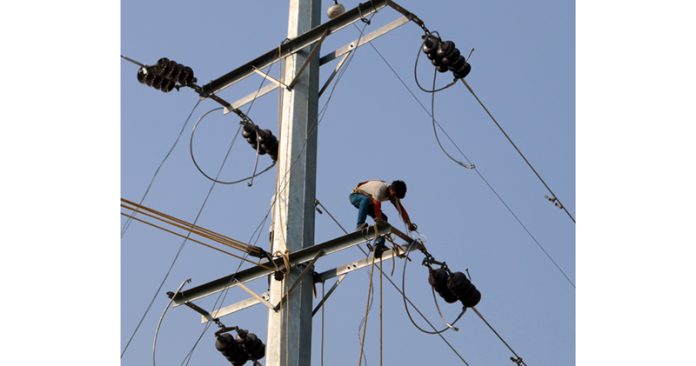 Risking life for earning livelihood: A PDD lineman works on a high tension electric pole in Jammu. -Excelsior/Rakesh