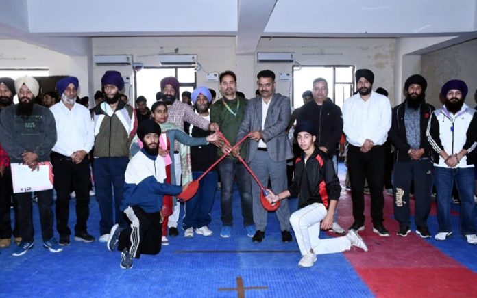 Gatka players pose for a photograph along with others at a district level competition in Jammu on Tuesday.