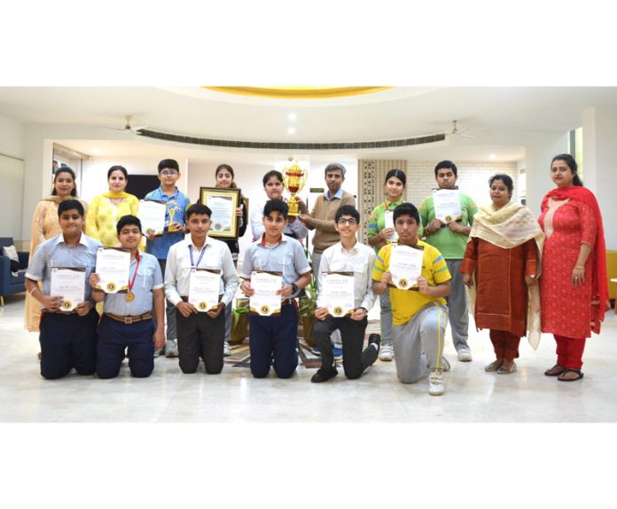 Students of GD Goenka Public School Jammu posing along with certificates, medals and a trophy.