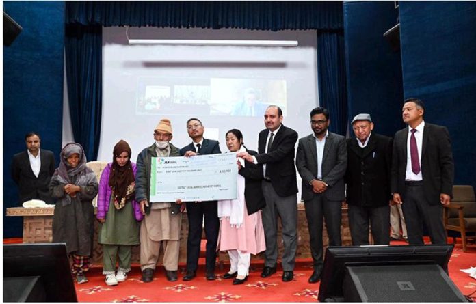 Justice Sanjeev Kumar, the Executive Chairman, LLSA presenting a cheque of compensation during a function in Kargil on Saturday.