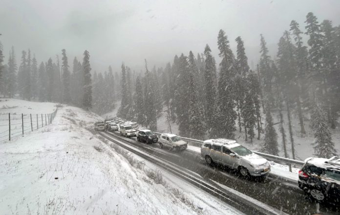 Vehicles moving on a road in Gulmarg amid fresh snowfall on Sunday. —Excelsior/Aabid Nabi