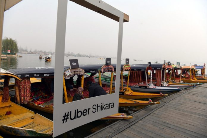 Shikaras lined up along Dal lake with an Uber Shikara sign in the background in Srinagar on Monday. - Excelsior/Shakeel