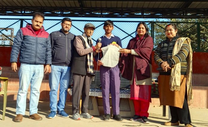 Social activist K K Wadhera, flanked by Principal Anuradha, and staff handing over cloth bags to a student at GHSS Bahu Fort in Jammu.