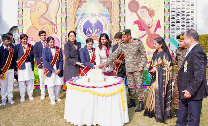 Dignitaries, management and students cutting a cake during annual day event at Akhnoor.