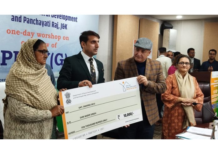 Minister Javed Ahmad Dar handing over cheque to a PMAY-G beneficiary on Thursday.