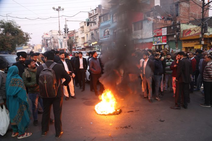 Protesting advocates burning a tyre on the Janipur road on Monday. — Excelsior/Rakesh