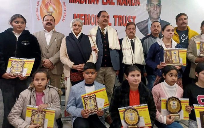 Guests posing with academic toppers during a function organized by MLN Memorial Trust in Reasi.