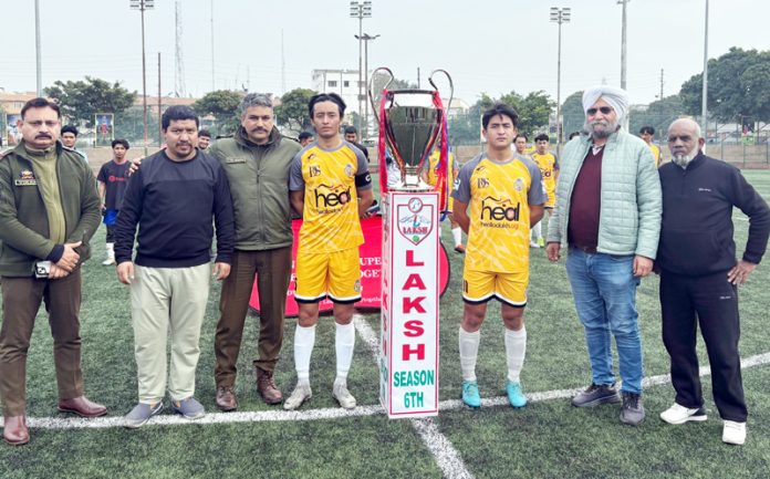 Dignitaries pose with the captains of the two teams alongside the LAKSH Trophy during the inaugural match at Parade Ground, Jammu, on Tuesday.