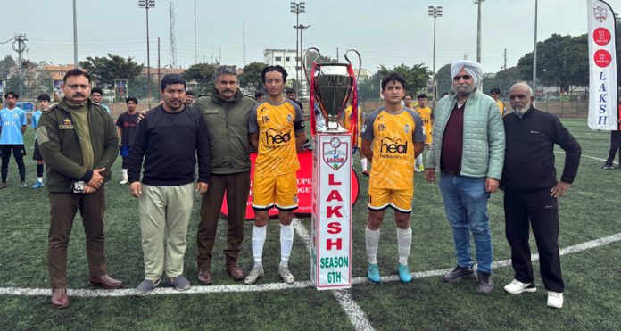 Dignitaries pose with the captains of the two teams alongside the LAKSH Trophy during the inaugural match at Parade Ground, Jammu, on Tuesday.