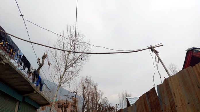 Electric wires on wooden poles and trees pose a danger in Bonezel Machan village of Ganderbal. -Excelsior/Firdous