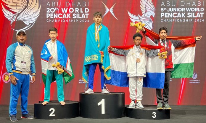 Ahmed Taha Masoodi proudly holding National flag on the podium with fellow winners after winning bronze at the 5th Junior World Pencak Silat Championship in Abu Dhabi.