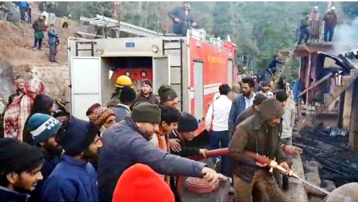 Fire fighters busy in dousing flames at a building in Ramban on Tuesday. -Excelsior/Parvez Mir