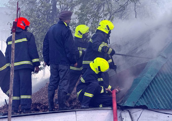 Fire fighters dousing a fire near the PDP office in Srinagar on Monday. (UNI)